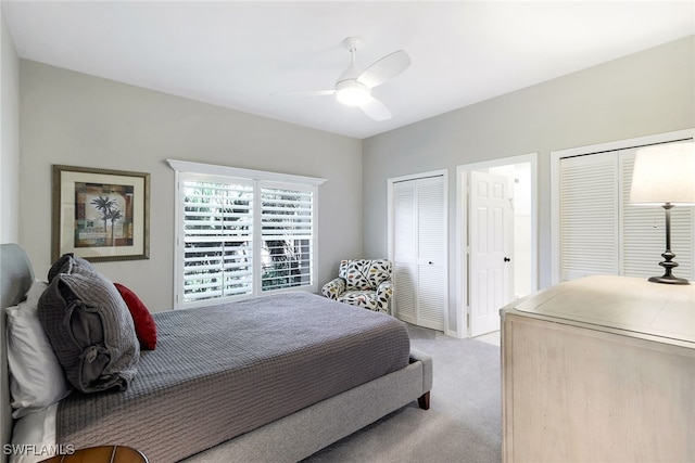 bedroom featuring multiple closets, light carpet, and ceiling fan