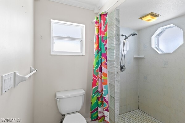 bathroom featuring curtained shower, a healthy amount of sunlight, and toilet