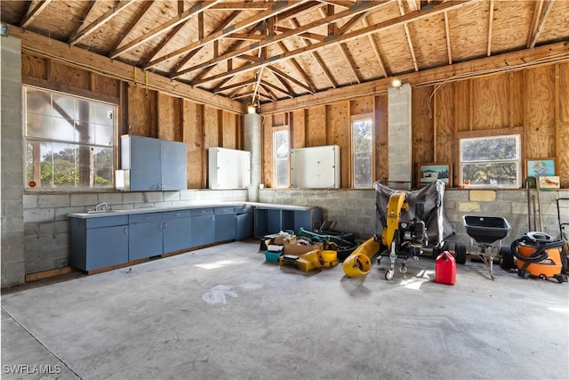 misc room featuring sink, high vaulted ceiling, and concrete floors