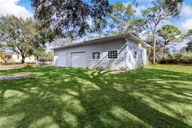 rear view of property featuring a lawn, a garage, and an outbuilding