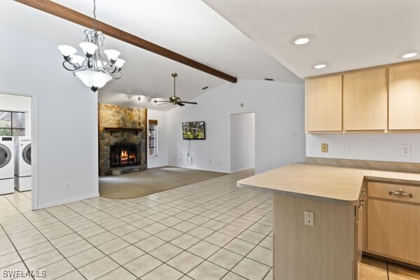 kitchen with ceiling fan with notable chandelier, a fireplace, decorative light fixtures, kitchen peninsula, and washing machine and clothes dryer