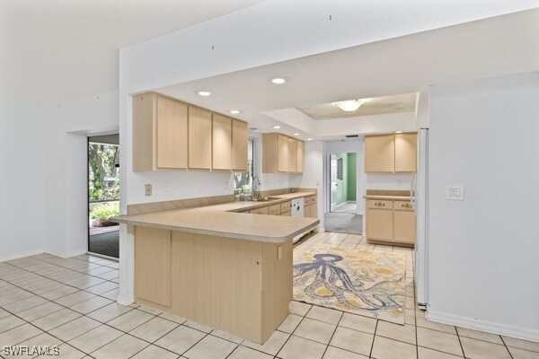 kitchen with white fridge, light tile patterned floors, kitchen peninsula, and light brown cabinetry