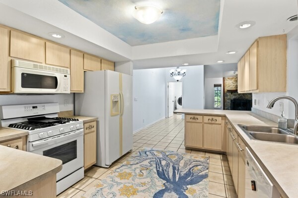 kitchen featuring light brown cabinets, white appliances, sink, light tile patterned floors, and kitchen peninsula