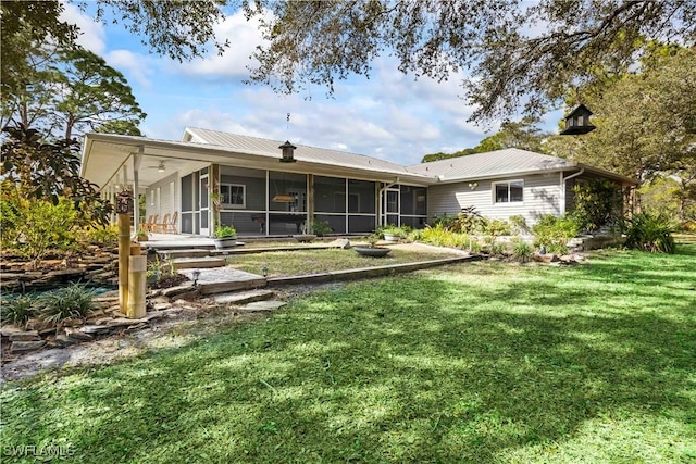 rear view of house featuring a lawn and a sunroom