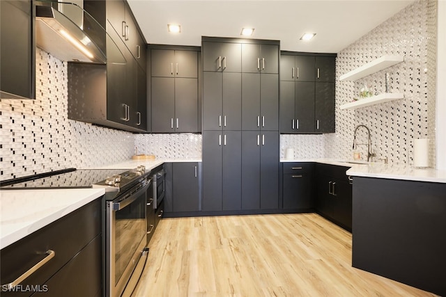 kitchen featuring sink, decorative backsplash, stainless steel range with electric stovetop, and light wood-type flooring