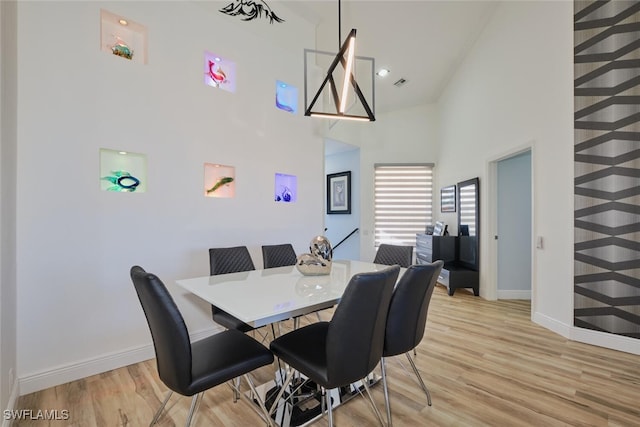 dining area featuring light hardwood / wood-style flooring and a high ceiling