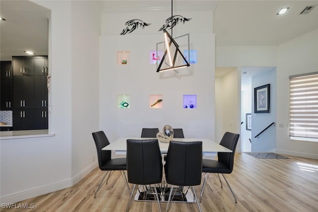 dining space featuring ornamental molding and light hardwood / wood-style flooring