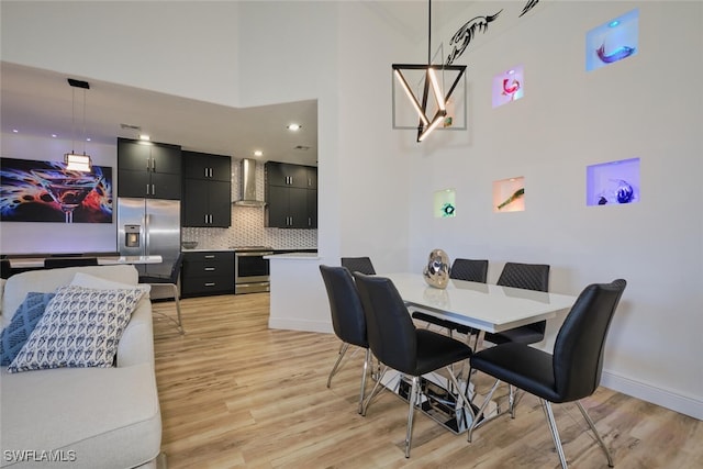 dining area with light hardwood / wood-style floors and a high ceiling