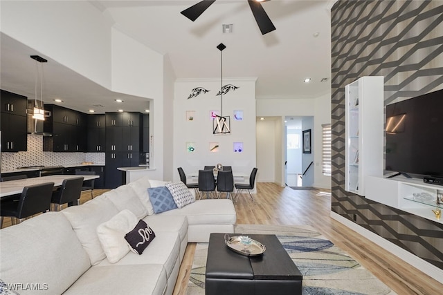 living room featuring crown molding, light wood-type flooring, and ceiling fan