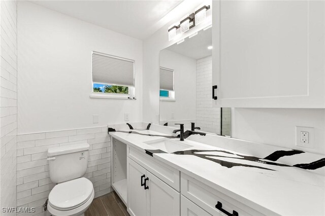 838-840 Rabbit Rd, Sanibel, FL 33957 - bathroom with wood finished floors, tile walls, a wainscoted wall, toilet, and vanity