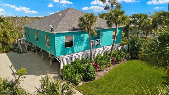 838-840 Rabbit Rd, Sanibel, FL 33957 - view of side of property featuring dirt driveway, a carport, stairs, and a shingled roof