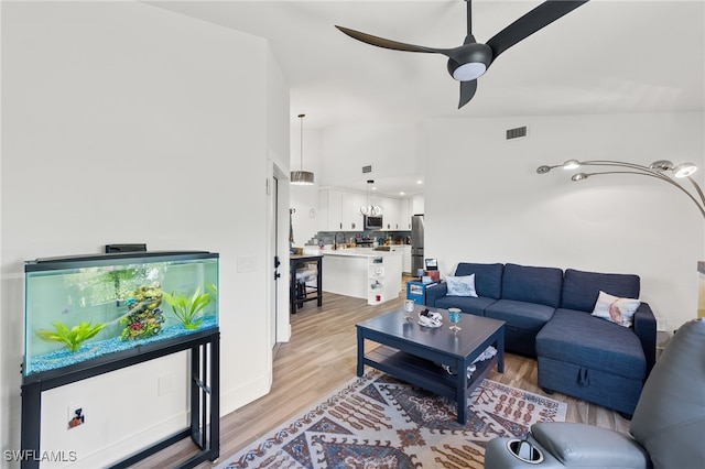 living room featuring light hardwood / wood-style floors, lofted ceiling, sink, and ceiling fan