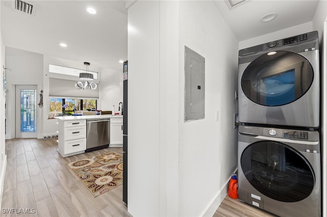 laundry room with electric panel, stacked washer / dryer, and light hardwood / wood-style floors