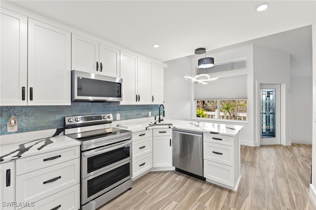 kitchen with appliances with stainless steel finishes, kitchen peninsula, and white cabinets