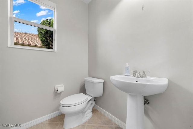 bathroom with toilet, sink, and tile patterned flooring