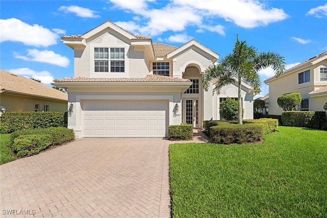 mediterranean / spanish home with a garage and a front lawn