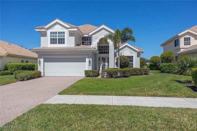 mediterranean / spanish home with stucco siding, a front lawn, a garage, a tiled roof, and decorative driveway