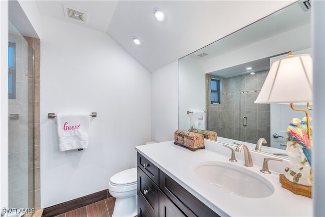 bathroom featuring a shower with door, hardwood / wood-style floors, toilet, vaulted ceiling, and vanity