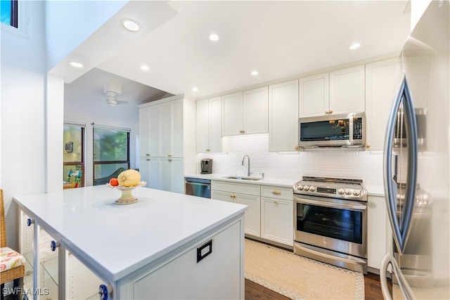 kitchen featuring tasteful backsplash, appliances with stainless steel finishes, sink, white cabinetry, and dark wood-type flooring