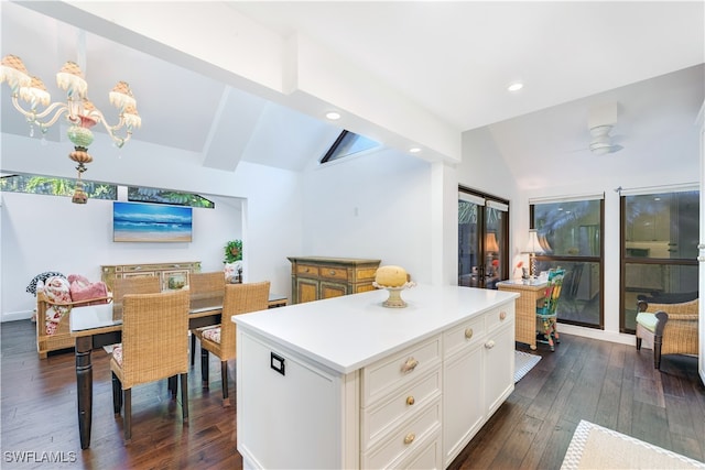 kitchen featuring vaulted ceiling with beams, ceiling fan with notable chandelier, a center island, white cabinetry, and dark wood-type flooring