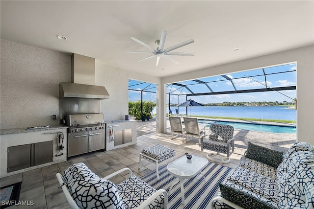 view of patio / terrace with a water view, a lanai, ceiling fan, an outdoor living space, and exterior kitchen