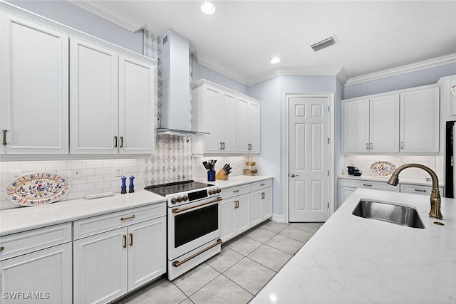 kitchen with electric stove, sink, white cabinetry, and wall chimney exhaust hood