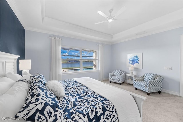 carpeted bedroom featuring ceiling fan, ornamental molding, and a tray ceiling