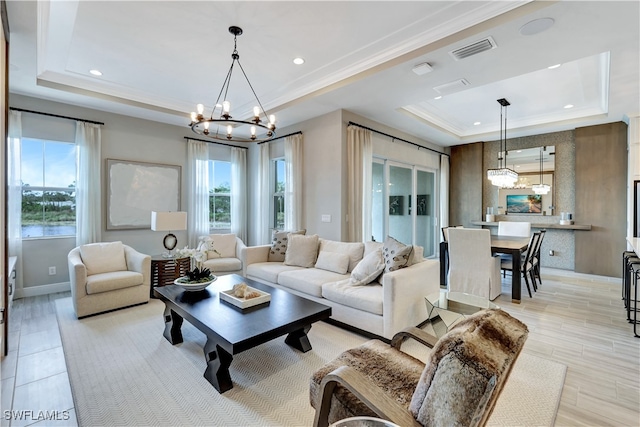 living room featuring a chandelier, light wood-type flooring, and a tray ceiling