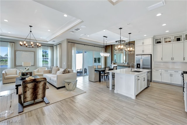 kitchen with decorative light fixtures, an island with sink, sink, and stainless steel appliances