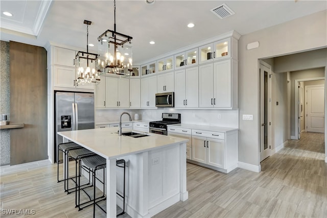 kitchen with white cabinets, stainless steel appliances, a kitchen island with sink, and sink