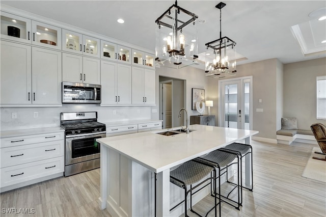 kitchen with white cabinetry, a kitchen island with sink, sink, and stainless steel appliances