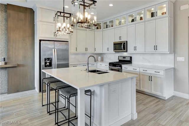 kitchen with white cabinetry, a kitchen island with sink, sink, and appliances with stainless steel finishes