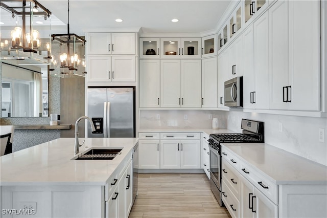 kitchen with white cabinetry, sink, decorative light fixtures, appliances with stainless steel finishes, and light wood-type flooring