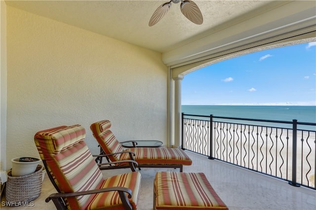 balcony with a view of the beach, ceiling fan, and a water view