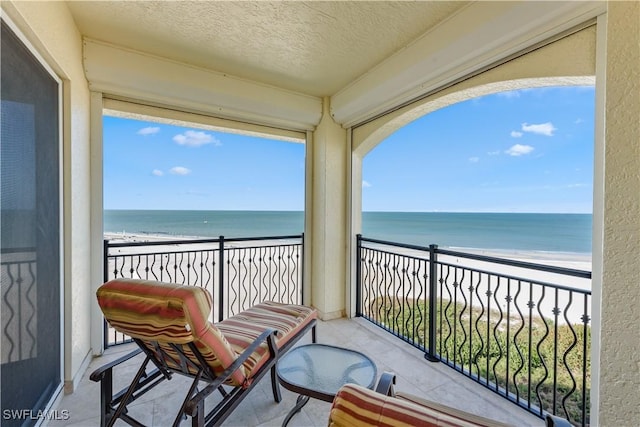 balcony featuring a water view and a view of the beach