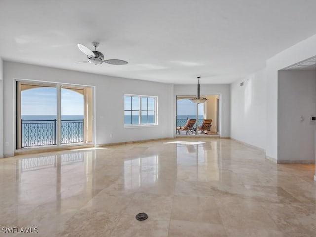 unfurnished room featuring a water view and ceiling fan with notable chandelier