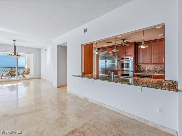 kitchen with tasteful backsplash, decorative light fixtures, stainless steel appliances, and dark stone counters