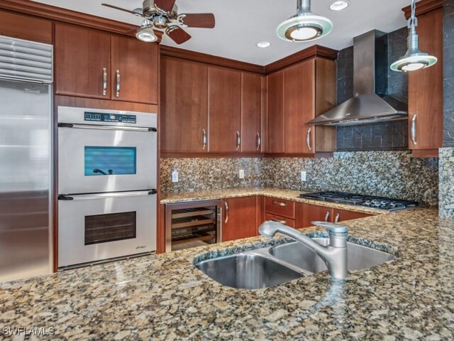 kitchen featuring pendant lighting, sink, beverage cooler, stainless steel appliances, and wall chimney range hood