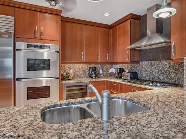 kitchen with appliances with stainless steel finishes, sink, beverage cooler, backsplash, and wall chimney exhaust hood