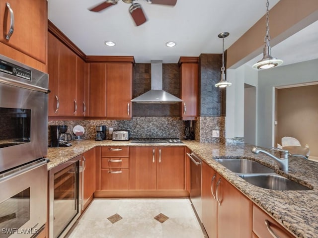 kitchen with appliances with stainless steel finishes, pendant lighting, sink, light stone counters, and wall chimney exhaust hood