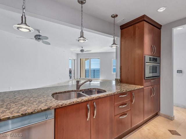 kitchen with sink, ceiling fan, appliances with stainless steel finishes, dark stone countertops, and hanging light fixtures