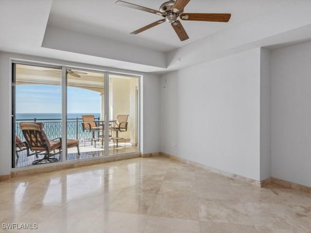 spare room with a raised ceiling, ceiling fan, and a water view