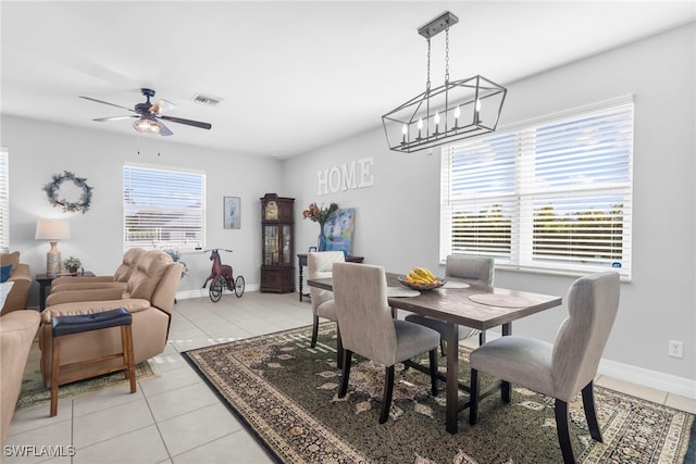 tiled dining space featuring ceiling fan with notable chandelier