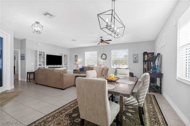 tiled dining room with ceiling fan with notable chandelier