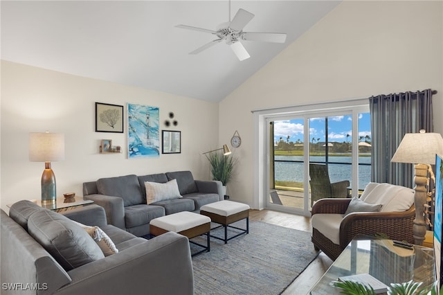 living room with ceiling fan, high vaulted ceiling, a water view, and light wood-type flooring