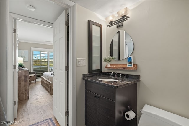 bathroom featuring toilet, crown molding, vanity, and wood-type flooring