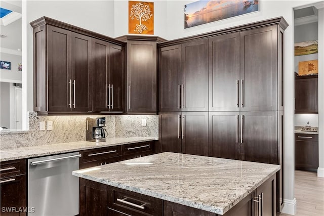 kitchen with tasteful backsplash, stainless steel dishwasher, dark brown cabinetry, and light stone countertops