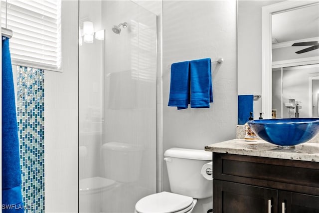 bathroom with vanity, ornamental molding, toilet, and a tile shower