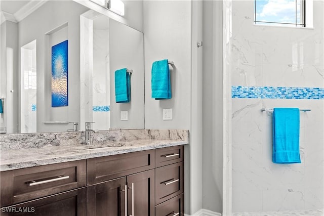 bathroom with vanity, a tile shower, and crown molding