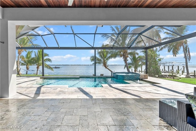 view of pool featuring a patio, an in ground hot tub, a water view, and glass enclosure